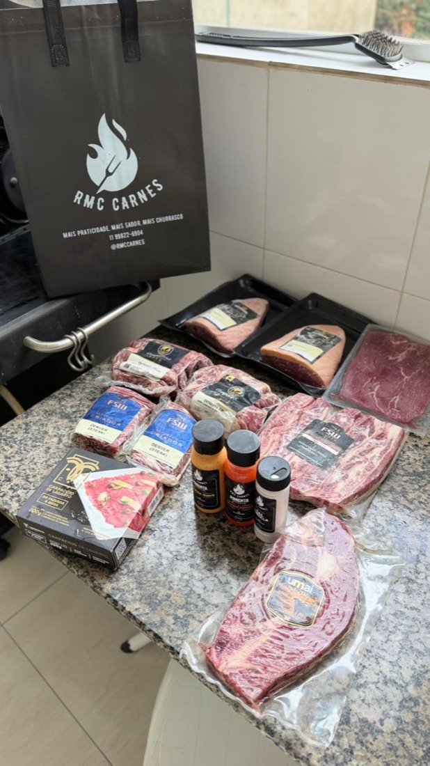 Kit RMC Carnes entregue: sacola da marca e cortes premium embalados sobre a bancada